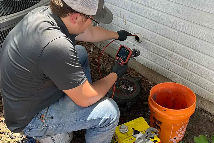 Plumbing technician inspecting a water line outside.